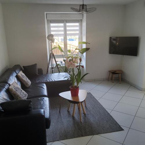 un salon avec un canapé noir et une table dans l'établissement L'Hôte du Malsaucy, à Évette