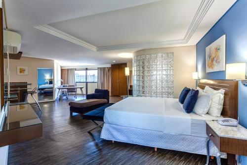 um quarto de hotel com uma cama grande e uma sala de estar em Blue Tree Towers Joinville em Joinville