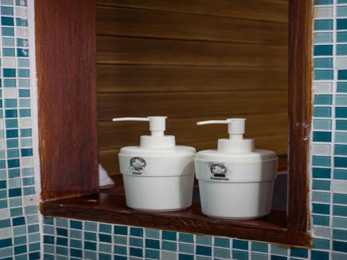 two white soap dispensers on a shelf in a bathroom at Maison de Cheer in Trang