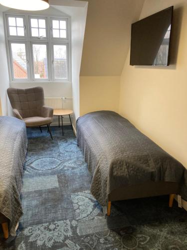 1 dormitorio con 2 camas, silla y ventana en Signinn en Varde