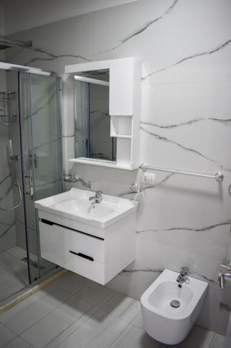 a white bathroom with a sink and a toilet at Gimi Apartments Shengjin in Shëngjin