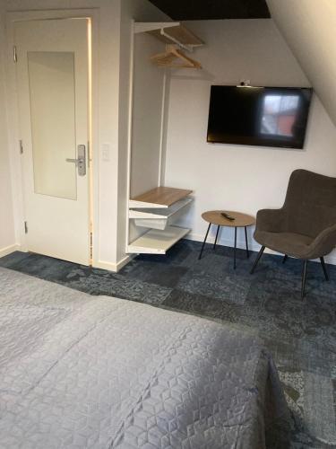 a bedroom with a bed and a chair and a tv at Signinn in Varde