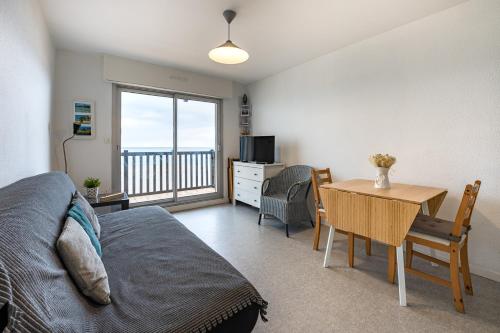 a bedroom with a bed and a desk with a table at Joli studio avec vue panoramique sur la Mer in Houlgate