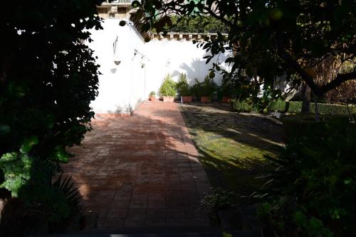 a brick walkway in a garden with a white wall at B&B Villa Maria in Giarre