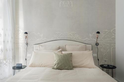 a bed with white sheets and pillows in a bedroom at Palazzo Ventimiglia Lodge & Suites in Palermo