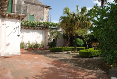 a courtyard with a building and a palm tree at B&B Villa Maria in Giarre