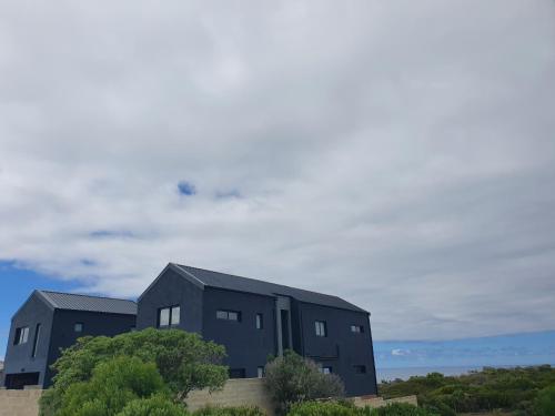 two black houses on the side of a hill at Southern most tip of Africa apartment with sea views in Agulhas