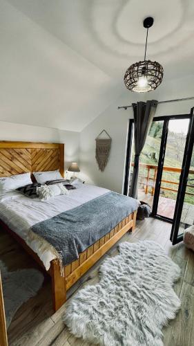 a bedroom with a large bed and a large window at Casa de Sub Munte Cozy Chalet in Fundata
