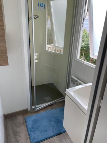 uma casa de banho com um chuveiro e um tapete azul em Mobil home 6 à 8 personnes SANS Fun Pass em Canet-en-Roussillon