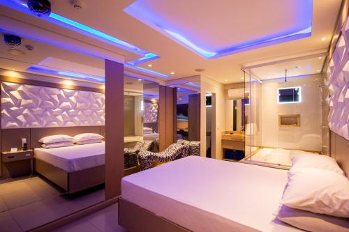 サンパウロにあるMotel Veleiros - Zona Norteの紫色の照明が備わるベッドルーム1室(ベッド2台付)