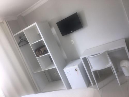 Jest to biały pokój z telewizorem i białym krzesłem. w obiekcie Emirates Hotel & Suites w mieście Santana do Livramento