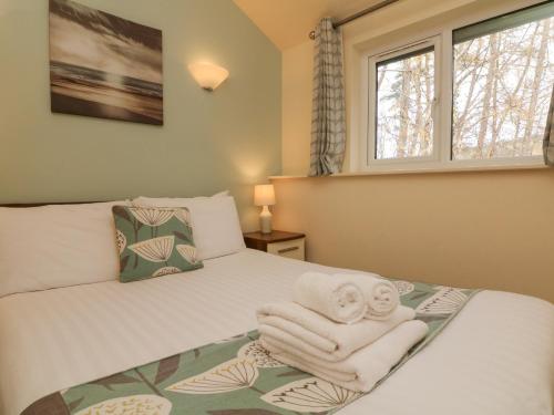 a bedroom with a bed with towels on it at Chalet Log Cabin L6 in Ilfracombe