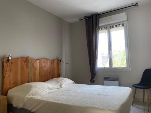 une chambre avec un lit, une fenêtre et une chaise dans l'établissement Séjour au cœur de Jard-sur-Mer : Maison avec terrasse et garage près de la plage ! - FR-1-336-125, à Jard-sur-Mer