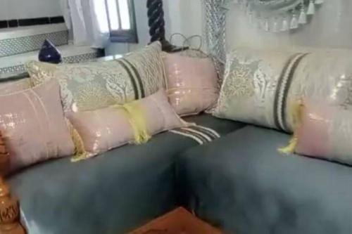 un sofá verde con almohadas rosas y blancas. en منزل فاخر مفروش للكراء بتارودانت en Taroudant