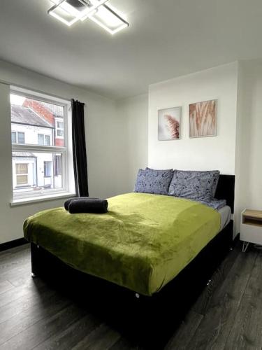 a bedroom with a green bed with a window at Newly refurbished city house with Hot Tub in Lincoln