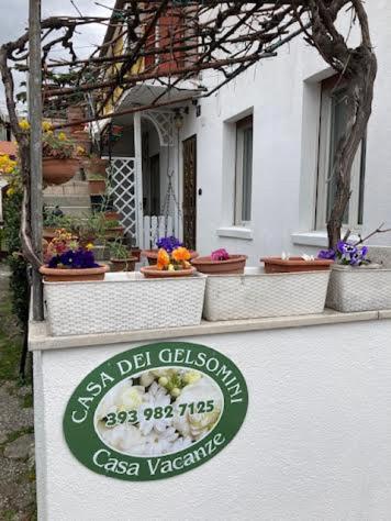 a sign in front of a white house with flowers at Casa dei Gelsomini in Trieste