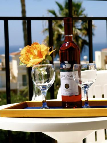 a bottle of wine and two glasses on a table at Hilltop Gardens Hotel Apartments in Paphos