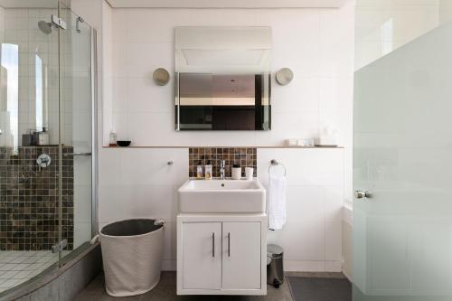 a white bathroom with a sink and a shower at #1701 Cartwright - Dark Glamour in Cape Town