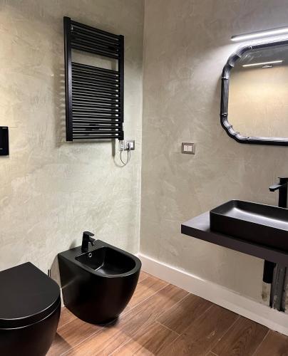 a bathroom with a black toilet and a sink at Alèa Rooms in Lecce