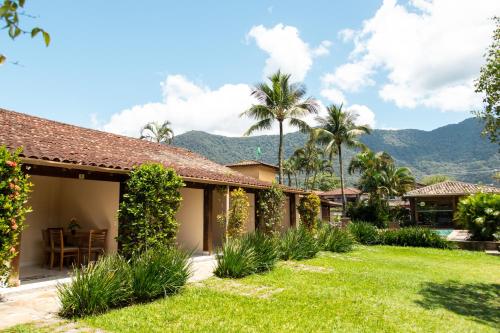 a house with a garden and mountains in the background at Arco Iris Chalés I in Maresias