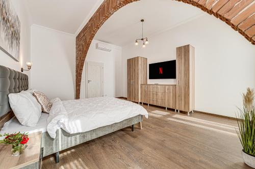 a bedroom with a bed and a tv on a wall at ARI Central Grand Apartment in Arad