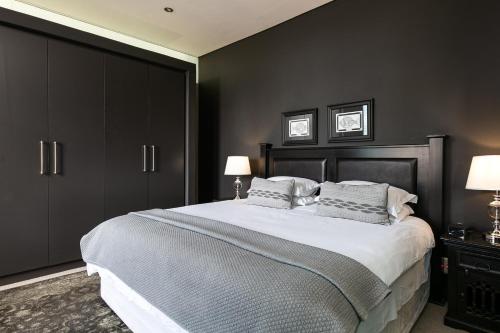 a bedroom with a large bed with black cabinets at #1701 Cartwright - Dark Glamour in Cape Town