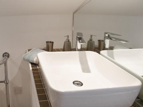 uma casa de banho com um lavatório branco num quarto em Ugly Duckling Cottage em Broughton in Furness