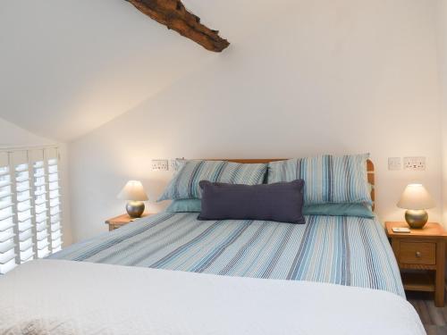 a bedroom with a bed with a blue pillow on it at Ugly Duckling Cottage in Broughton in Furness