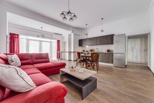 a living room with a red couch and a kitchen at ARI Central Grand Apartment in Arad
