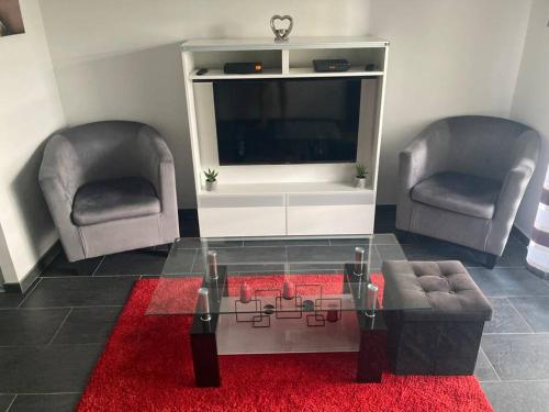 a living room with two chairs and a table and a tv at Magnifique studio tout équipé classé 2 étoiles in Saint-Leu