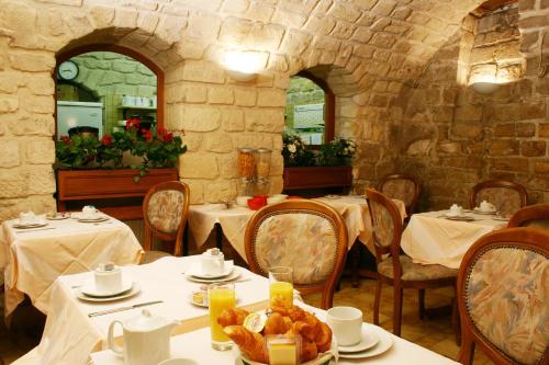 un restaurante con mesas blancas y sillas con comida. en Hotel Meslay Republique en París