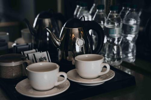 two cups and saucers on a table with a tea kettle at Sidra International Hotel in Addis Ababa
