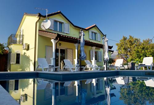 a house with chairs and a swimming pool at Relax House Nizic in Dražice