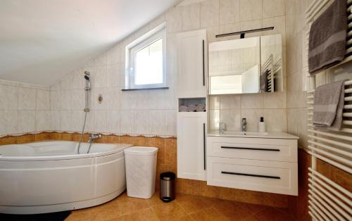 a white bathroom with a tub and a sink at Relax House Nizic in Dražice