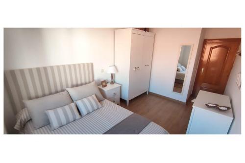 a small bedroom with a bed and a mirror at El Balcón del Campillín in Oviedo