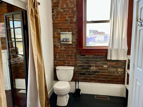 a bathroom with a toilet and a brick wall at Downtown Loft Sleeps 6 - Pool Table Shuffleboard in Louisville