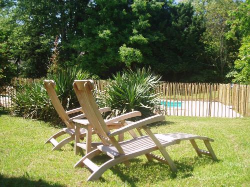 two wooden chairs sitting in the grass in a yard at La Cerisaie - Chambres d'hôtes & gites in Riols
