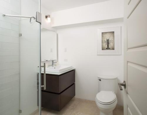 a white bathroom with a toilet and a sink at Azura Bermuda in Bermuda