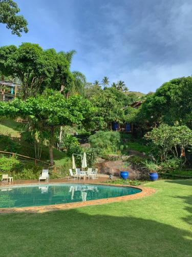 a pool in a yard with chairs and a table at Casas D'Água Doce - Casa Luz in Ilhabela