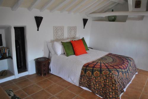 een slaapkamer met een bed met rode en groene kussens bij Casa Miguel Montefrio in Granada