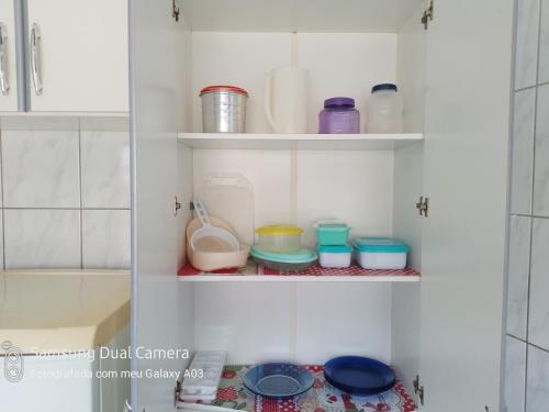 une armoire remplie de assiettes et de bols dans une salle de bains dans l'établissement Casa temporada paraíso, à Cabo Frio