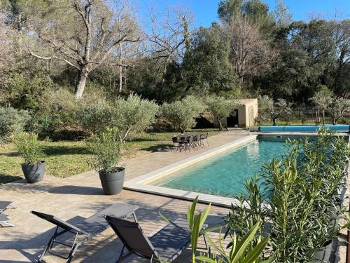 una piscina con sillas, mesa y árboles en Les micocouliers en Lagnes