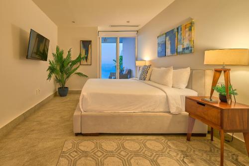 a bedroom with a bed and a table with a lamp at Maxwell Residences at Indah in Puerto Vallarta
