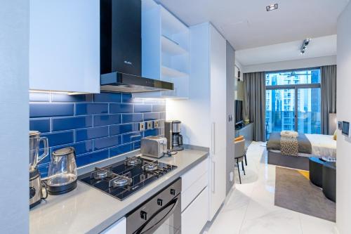 a kitchen with blue tiles on the wall at Lux Studio in Downtown, 5 mins to Burj Khalifa & Dubai Mall - MAG318 in Dubai