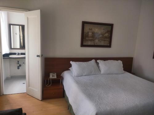 a bedroom with a bed and a sink and a mirror at Hotel Bella Montaña in Manizales