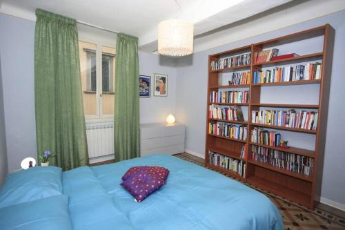 ein Schlafzimmer mit einem blauen Bett und einem Bücherregal in der Unterkunft Dimora Puccini in Lucca