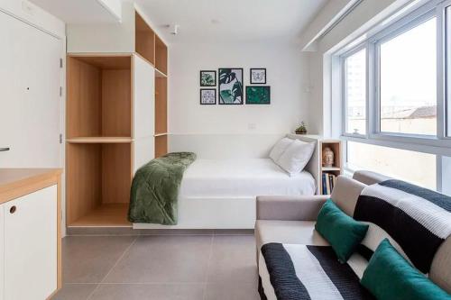 a white living room with a couch and a window at Studio Harmonia, Moderno, Aconchegante e com Garagem in Sao Paulo