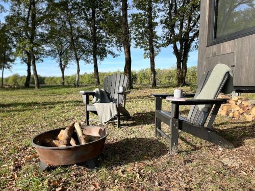 eine Feuerstelle und zwei Stühle neben einem Gebäude in der Unterkunft L'Envolée Ecolodge, tiny house au coeur des vignes in Loches-sur-Ource