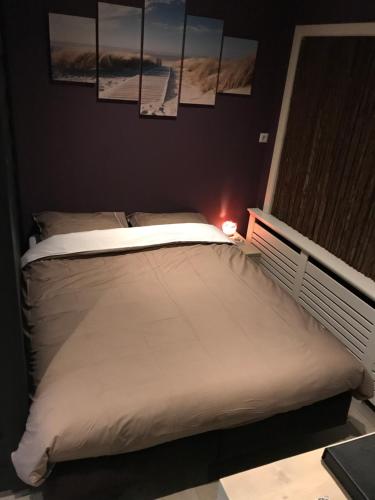 um quarto com uma cama branca com fotografias na parede em Zeeuws Ontspannen Bed & Wellness em Middelburg