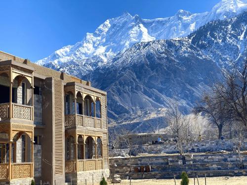 a building with snowy mountains in the background at Dumani Nagar Hotel & Resort in Hunza Valley